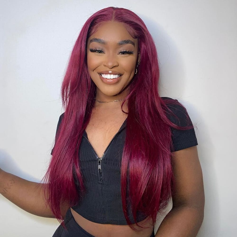 A young woman beams at the camera, showcasing her long, straight, vibrant burgundy hair.