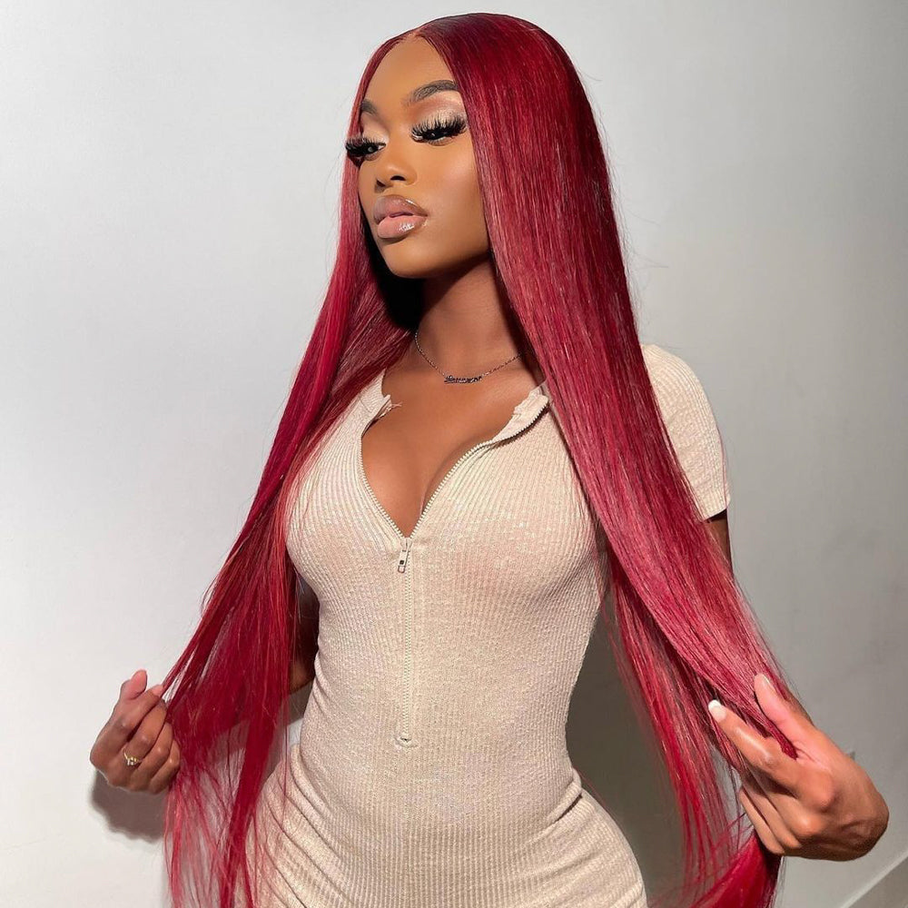 Long Red Hair Model Wearing a Beige Bodycon Dress and Holding Her Burgundy Colored Hair Wig in Front of a White Background